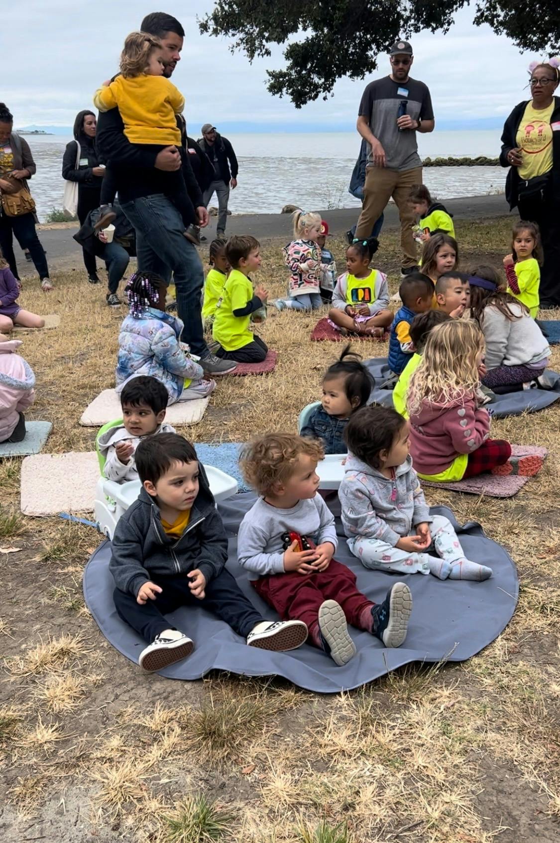 Adults and children gathered outdoors near water