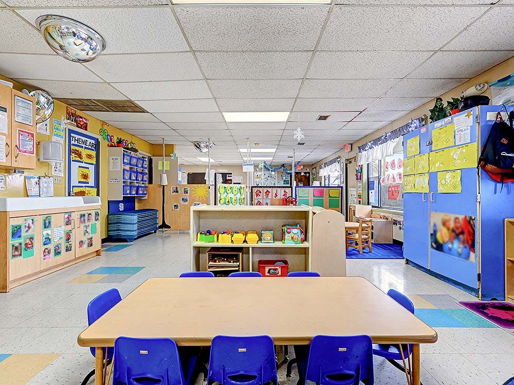 Empty colorful daycare or preschool classroom with small tables and chairs