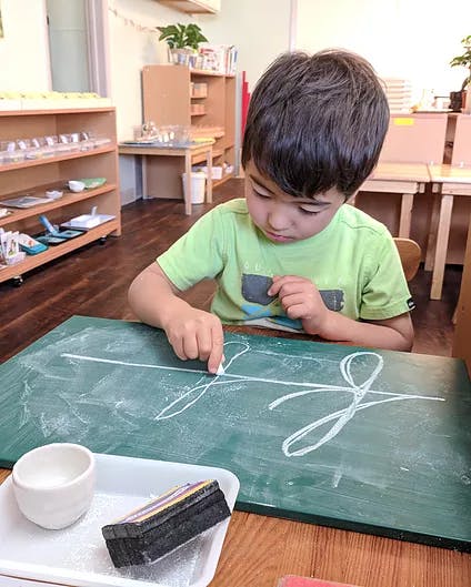 Child writing on a chalkboard with chalk