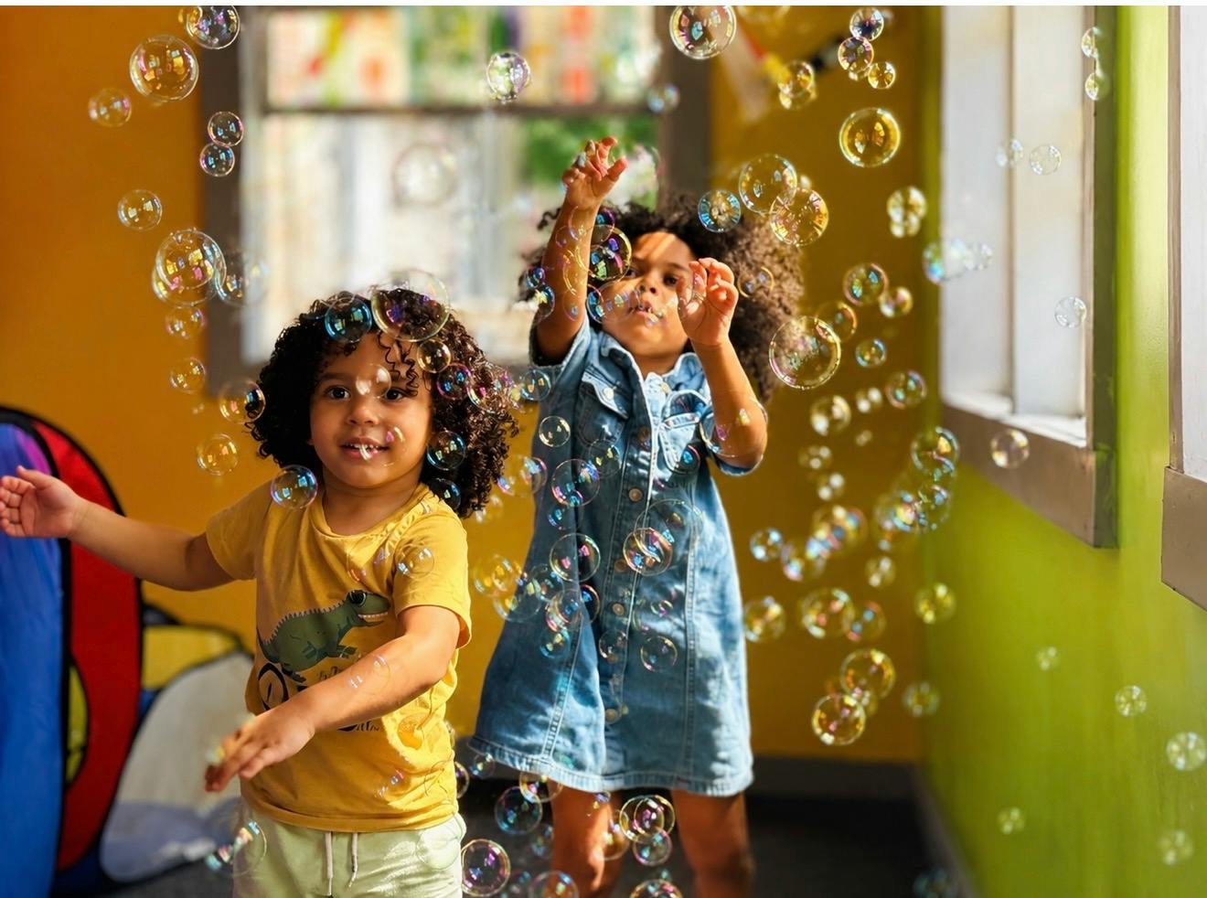 Two children playing with bubbles indoors