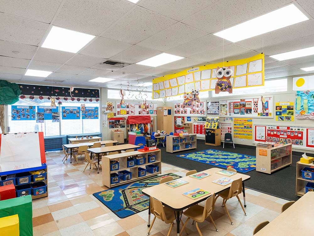 Empty kindergarten classroom with tables, chairs, and colorful decorations