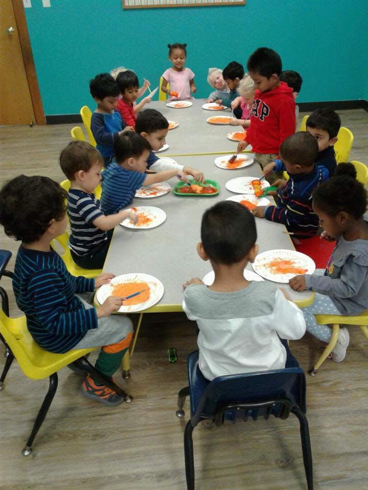 Children sitting at a table with plates and craft supplies