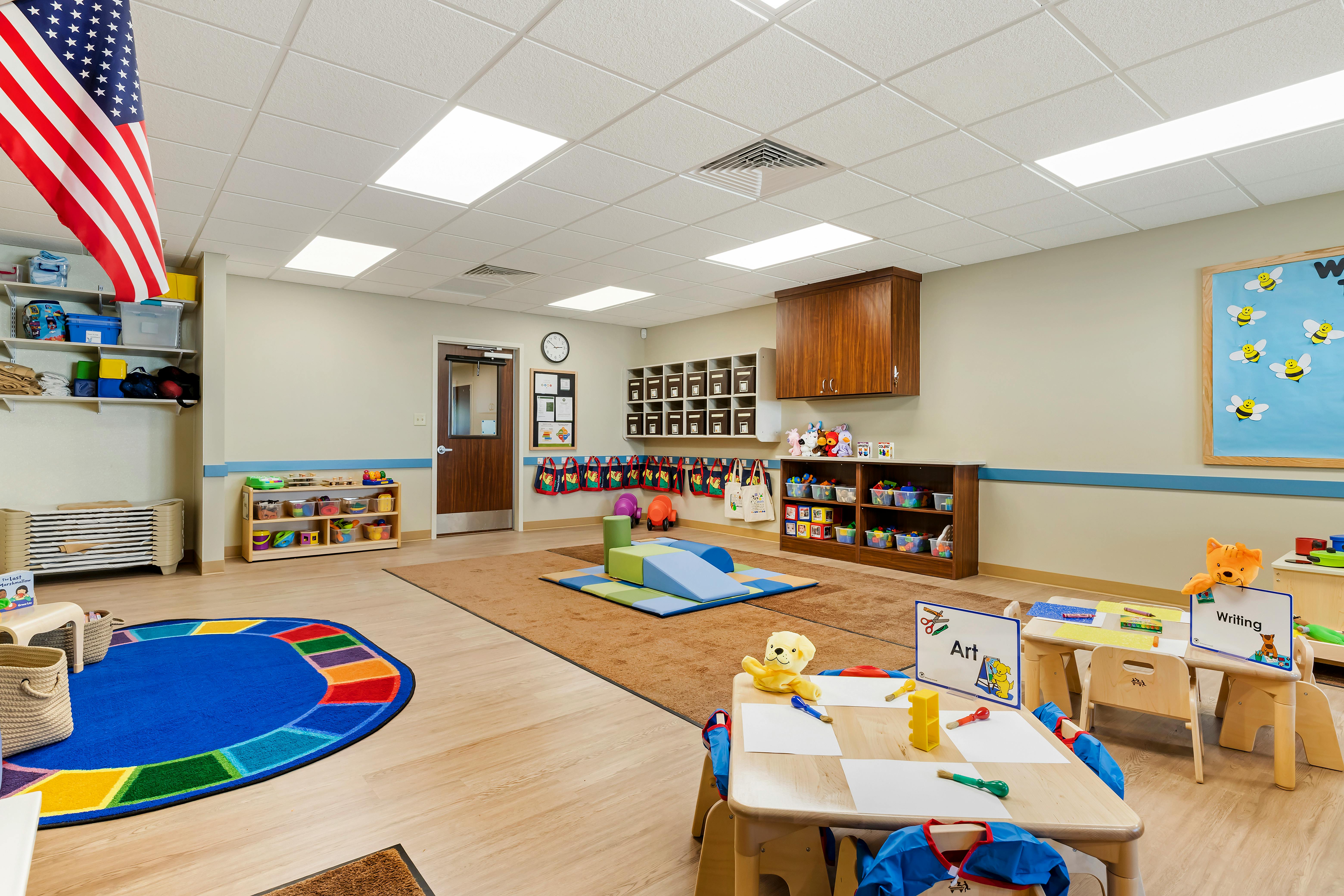 A classroom for young children with an American flag hanging from the ceiling