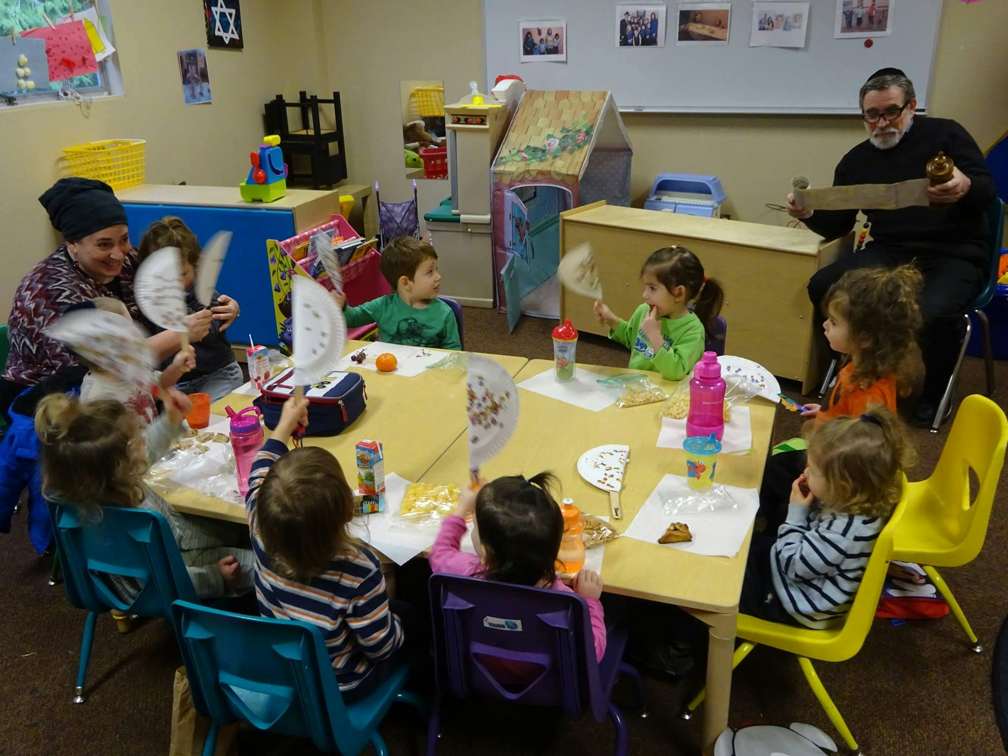 Adults and children sitting at tables in a classroom