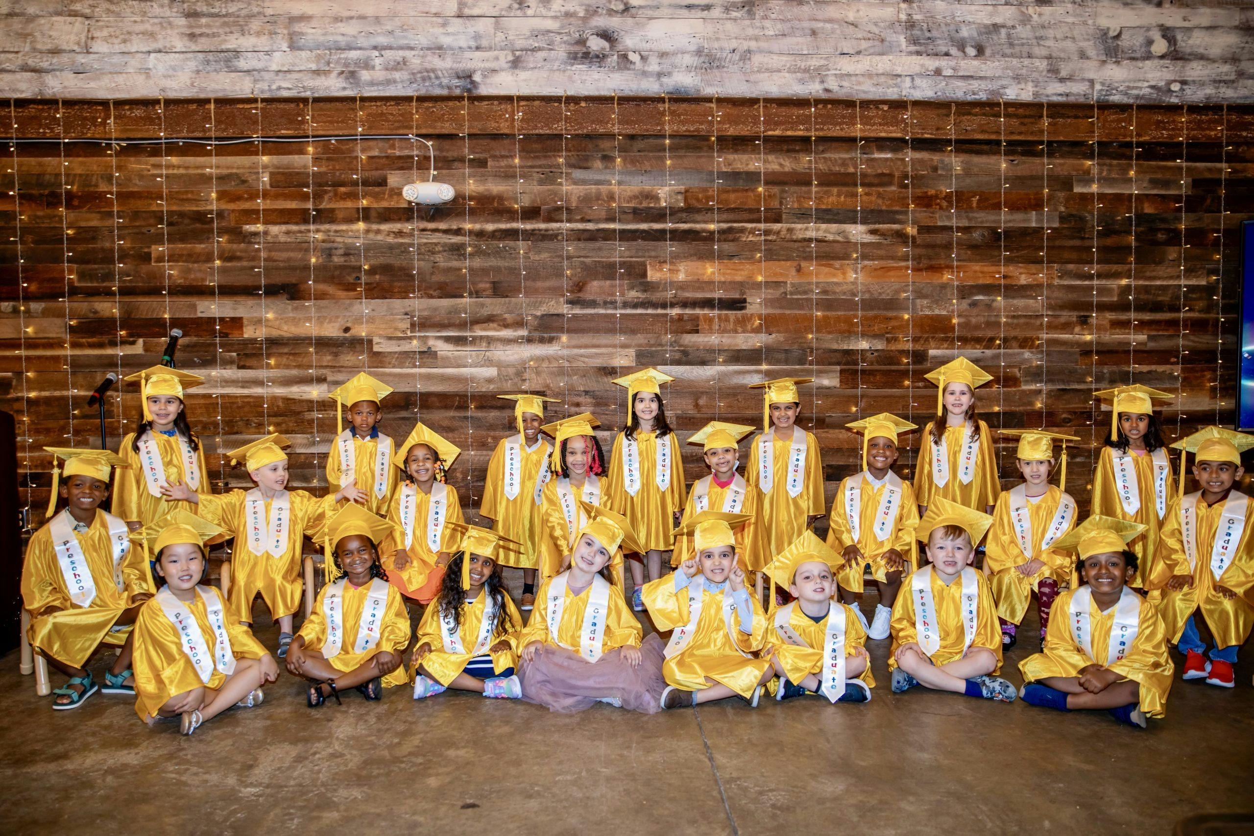 Group of children in yellow graduation caps and gowns