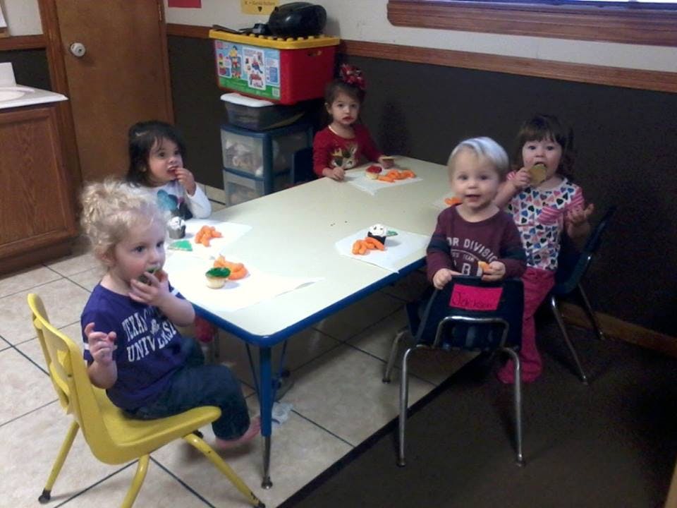 Five children sitting at a table eating snacks