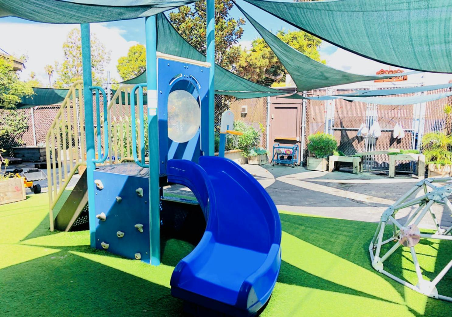 Blue playground slide and climbing structure on green turf
