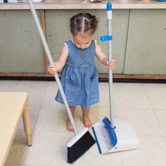 Child sweeping with a broom and dustpan