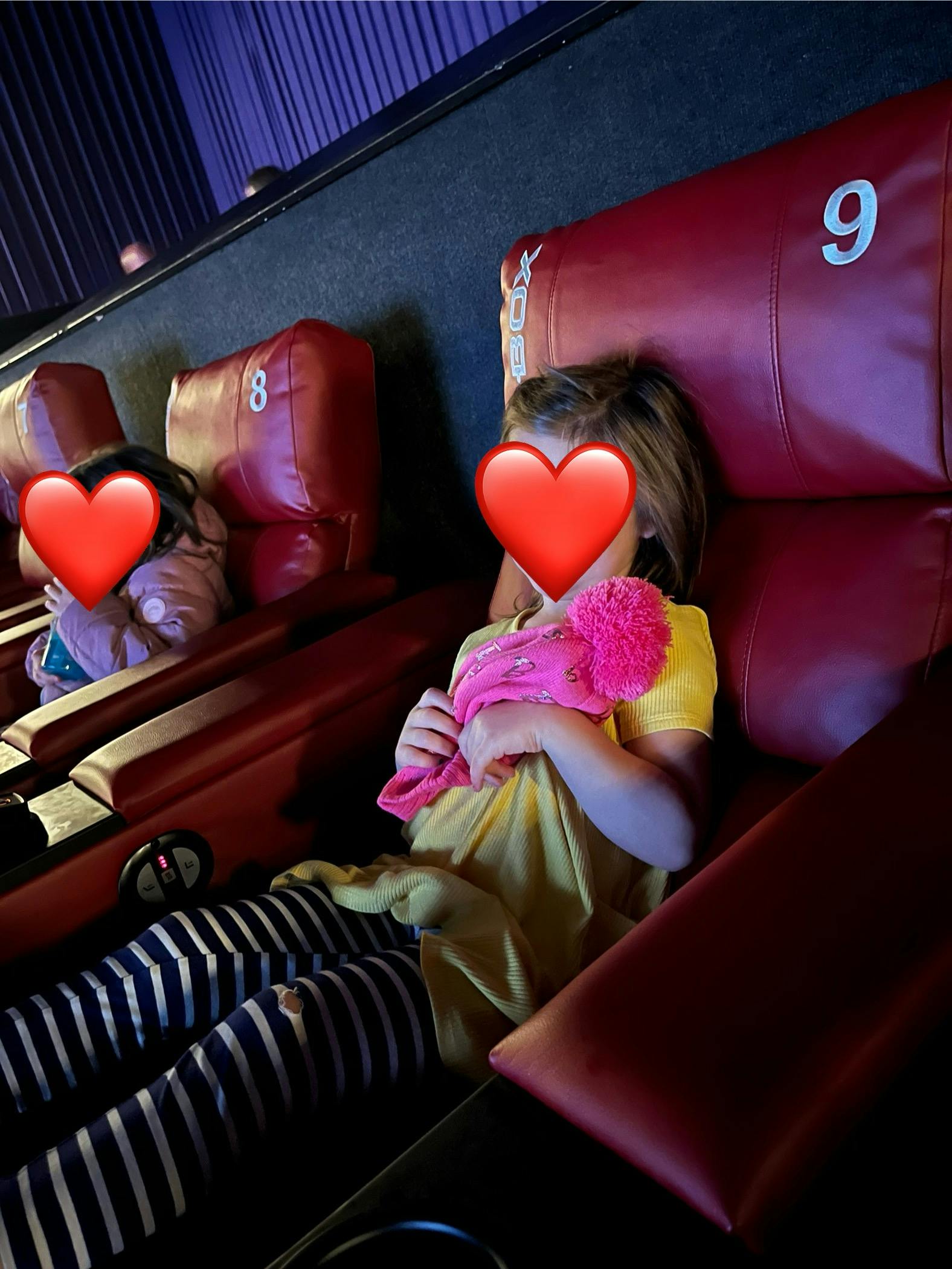 Two children sitting in red cinema theater seats