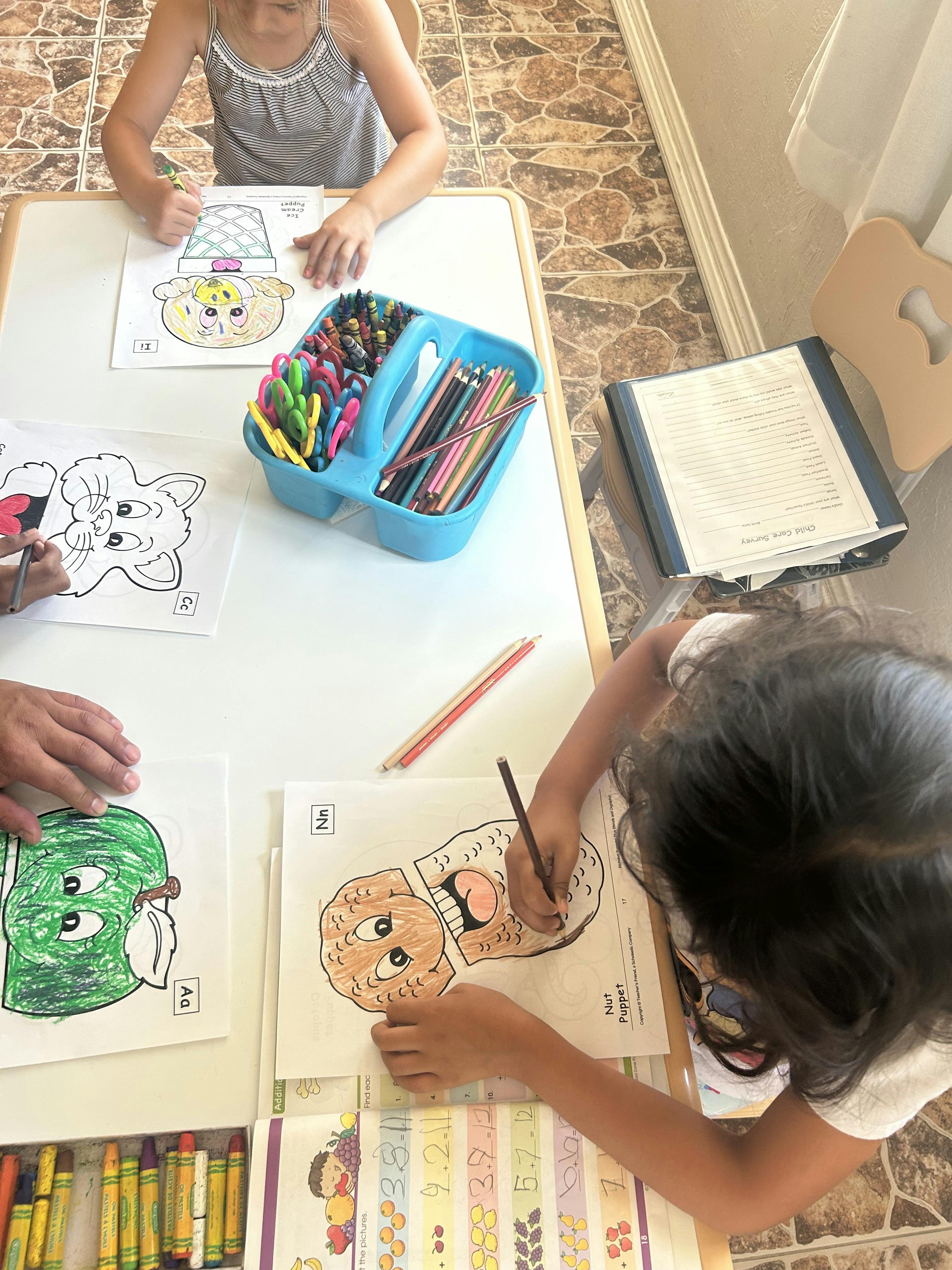 Children coloring at a table with crayons and colored pencils