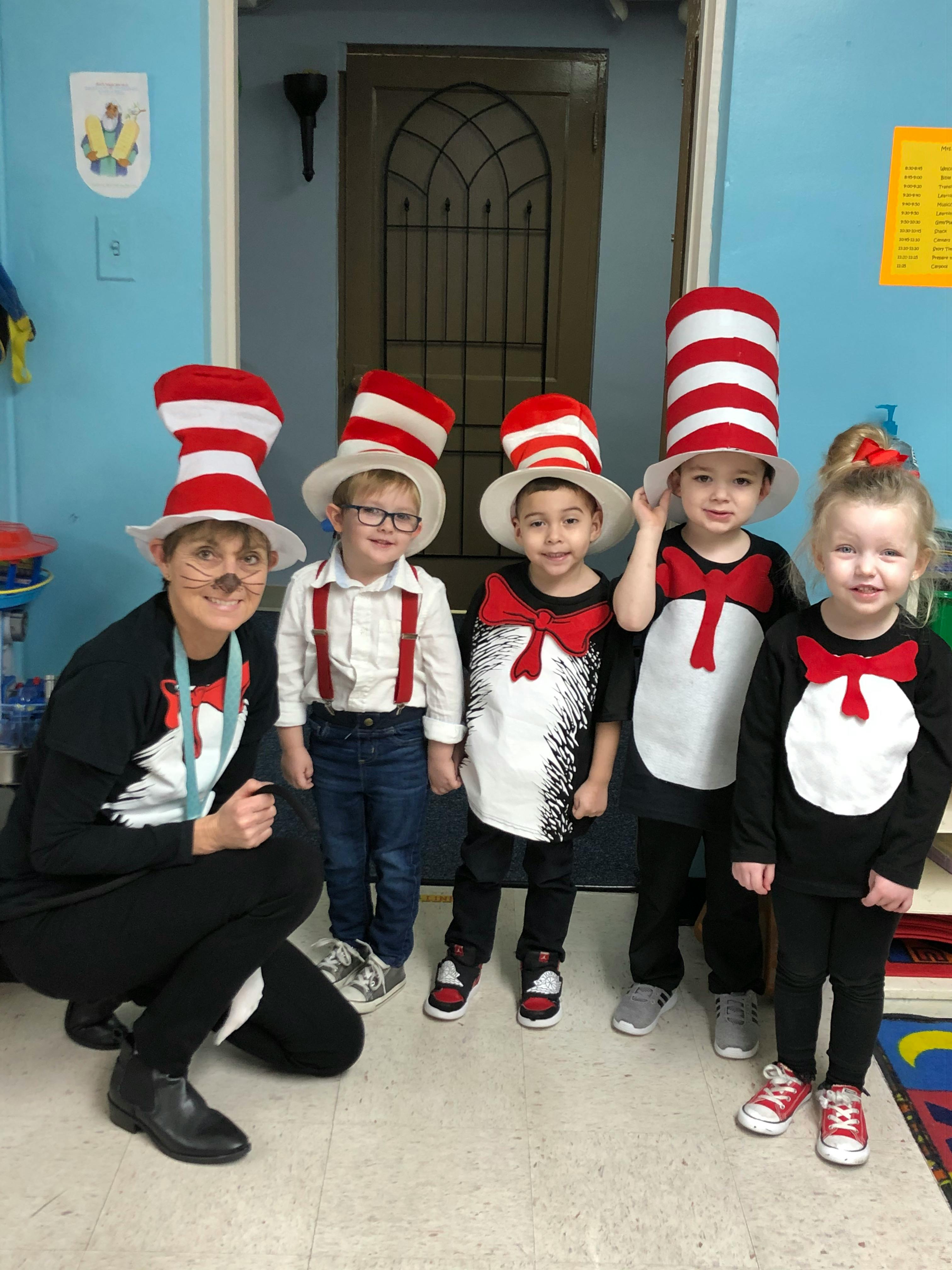 Person and four children in red and white striped hats and costumes