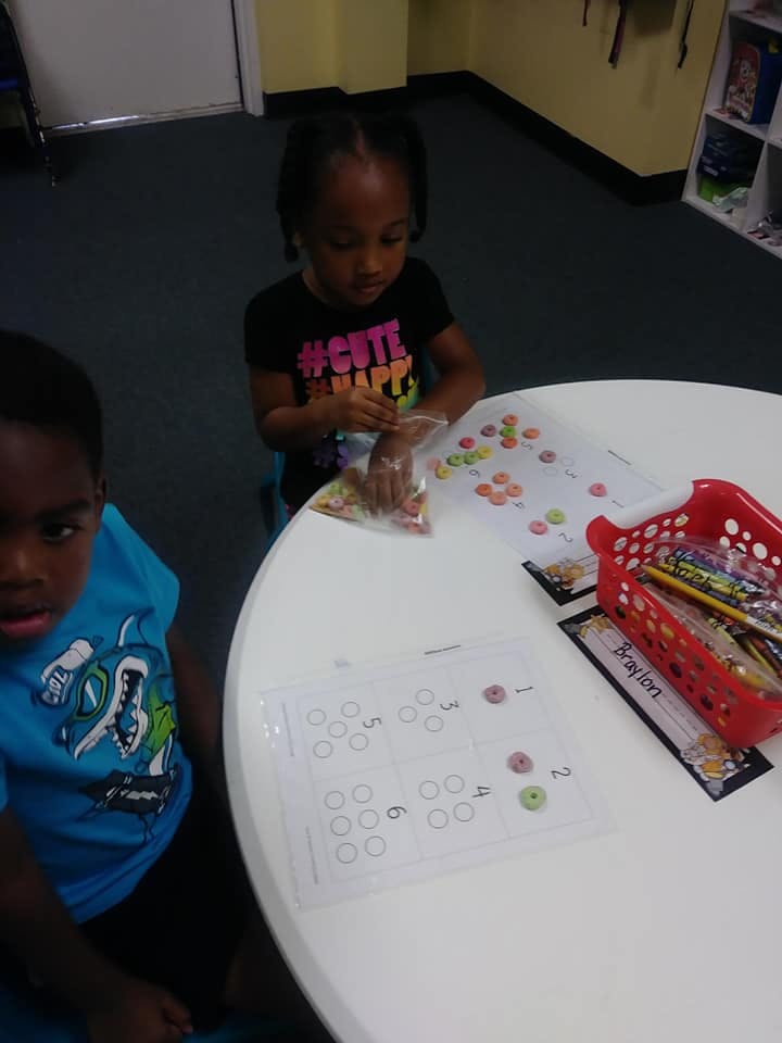Child sorting small colorful objects on a worksheet at a table