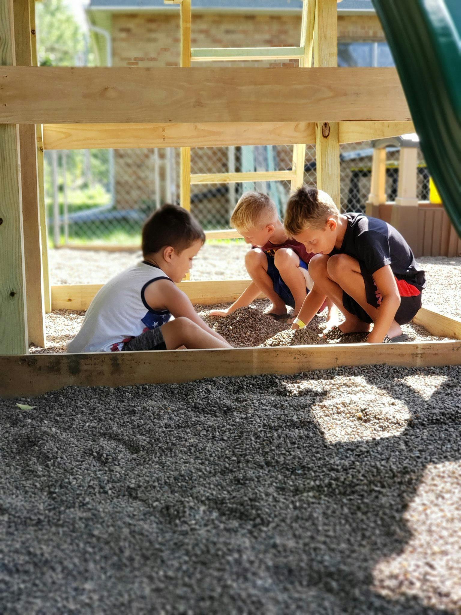 Three children playing in a sandbox