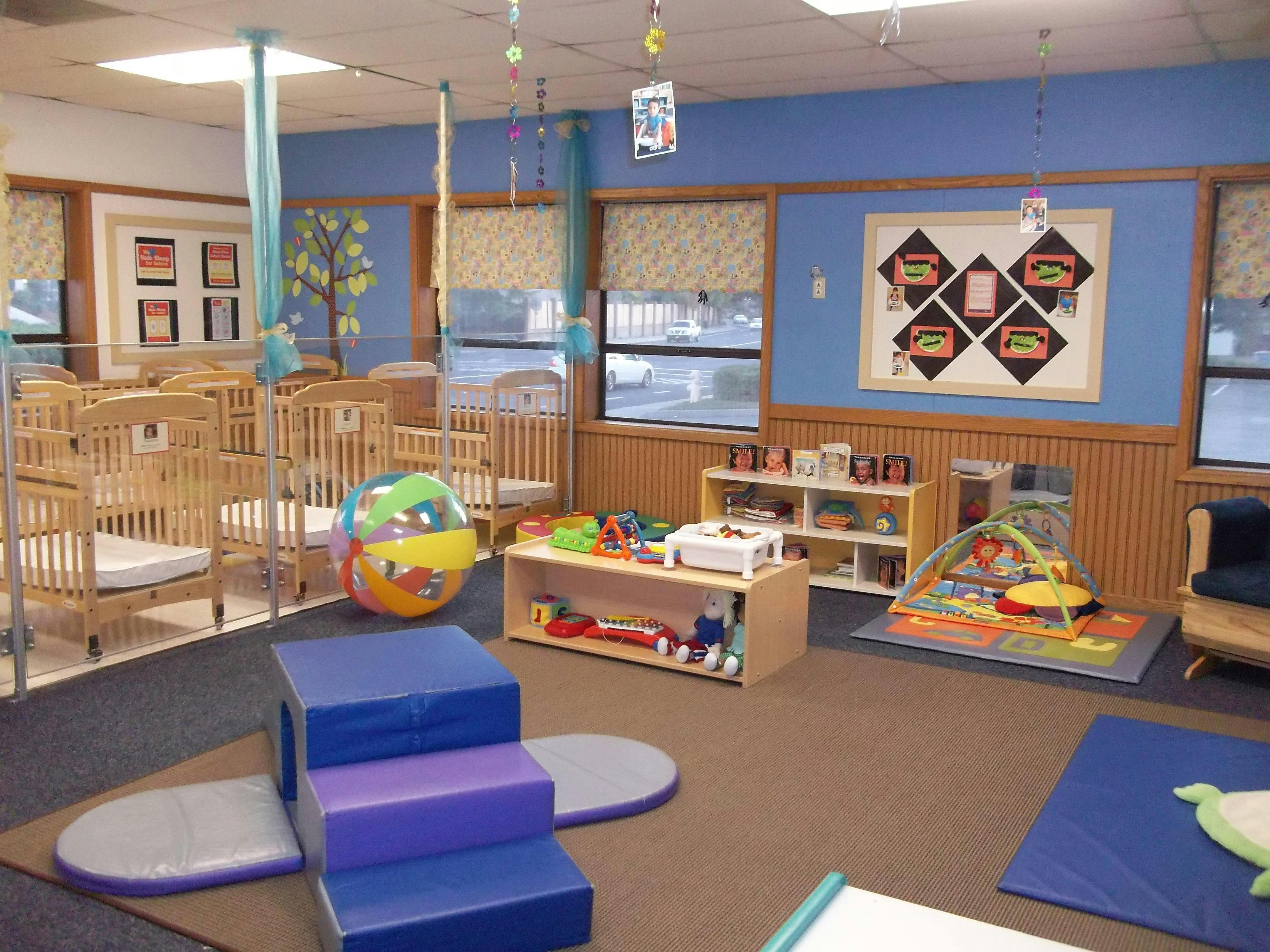 daycare classroom with multiple cribs, a play mat, and toys