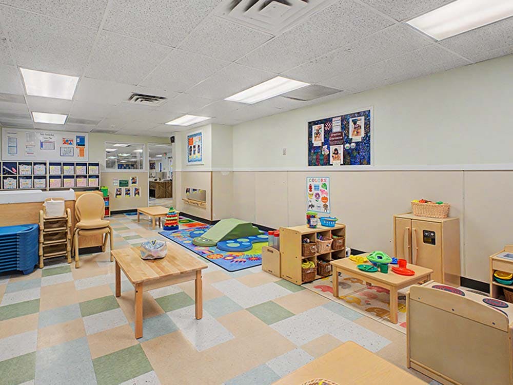 An empty early childhood classroom with small tables and chairs