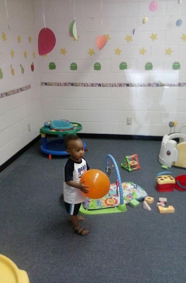 Child holding an orange ball in a playroom