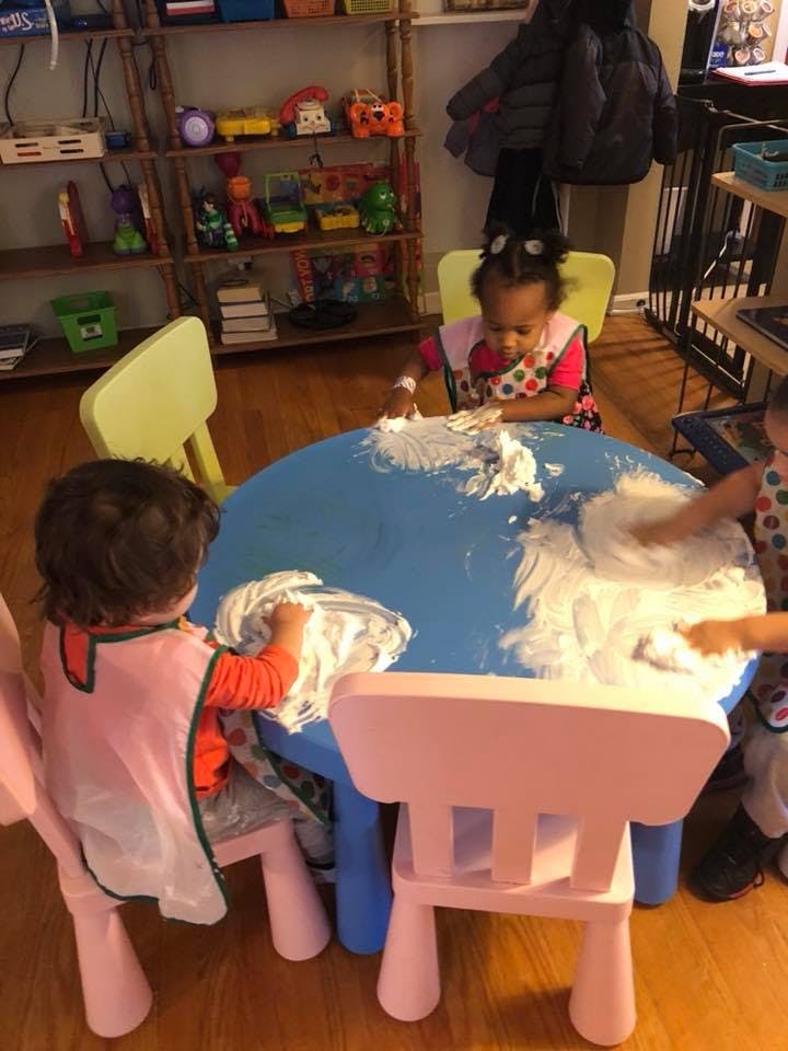 Children playing with shaving cream at a blue table