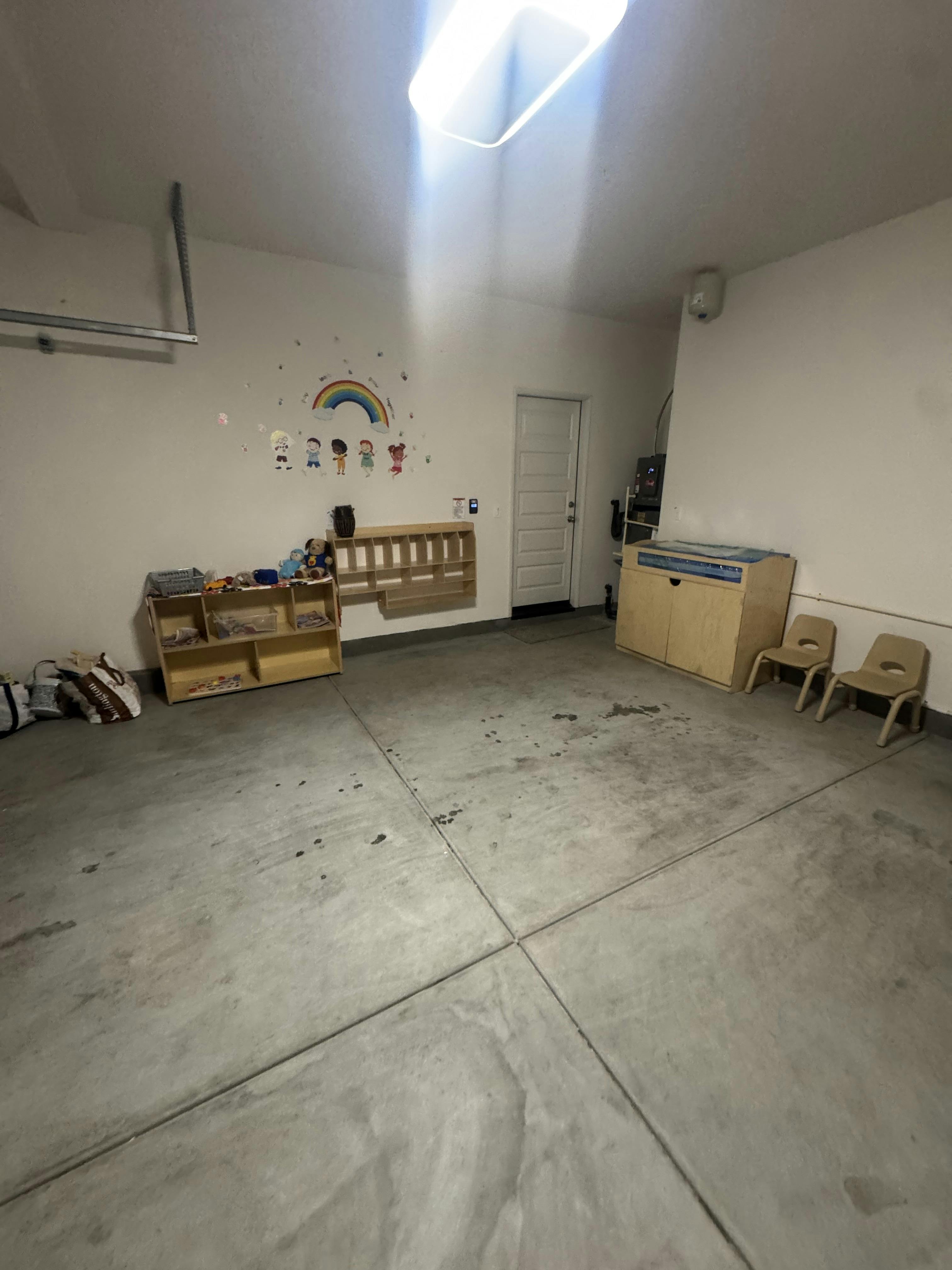 Garage converted into a learning space with wall decals, shelves, and small chairs