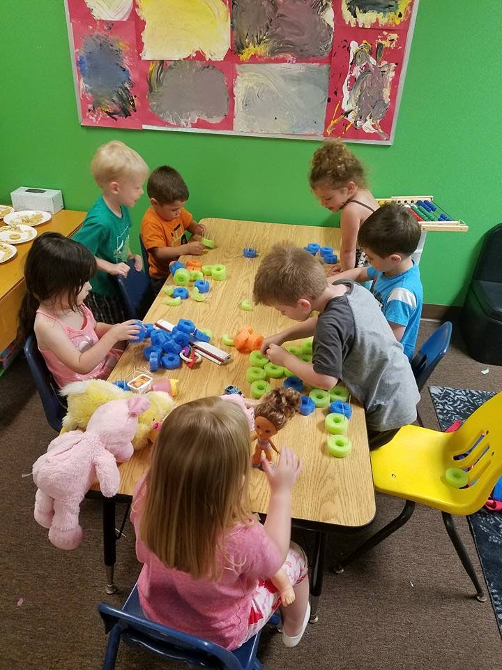 Children playing with toys at a table in a classroom