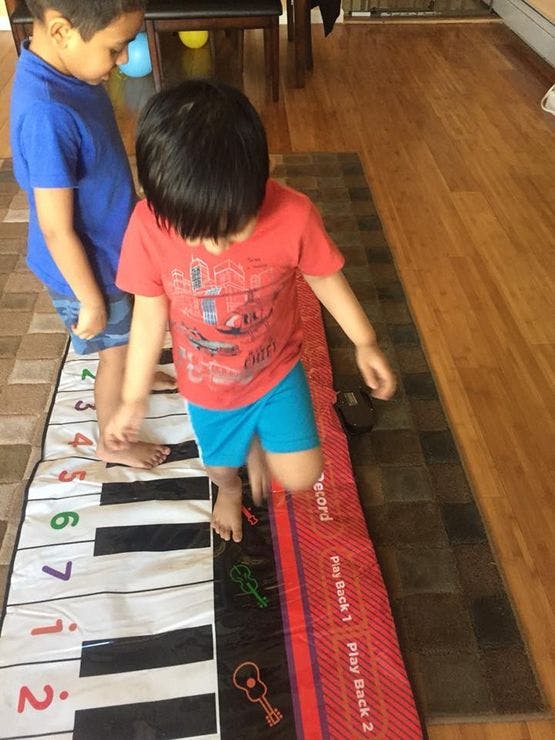 Two children playing on a floor piano mat