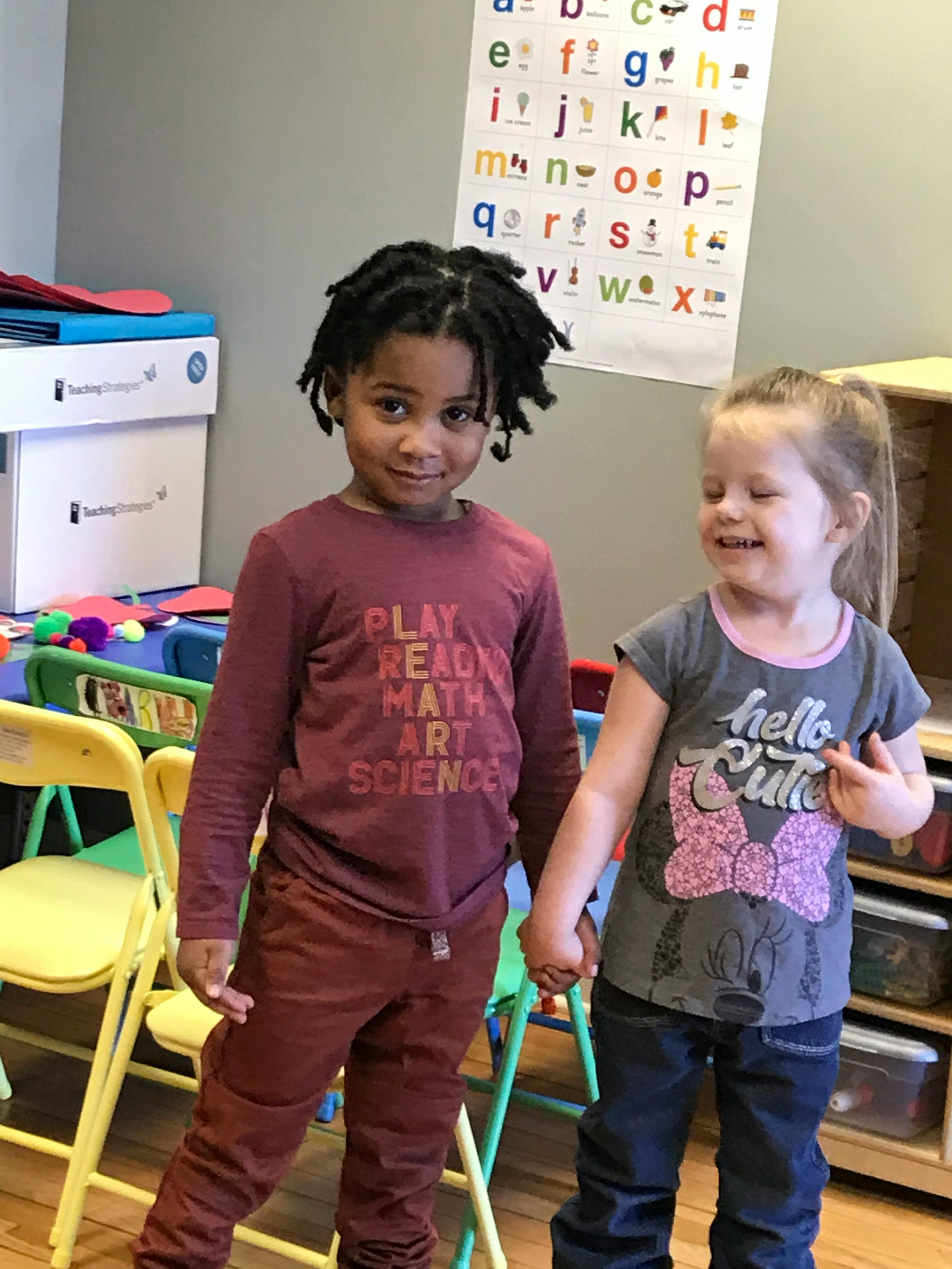 Two children holding hands in a classroom