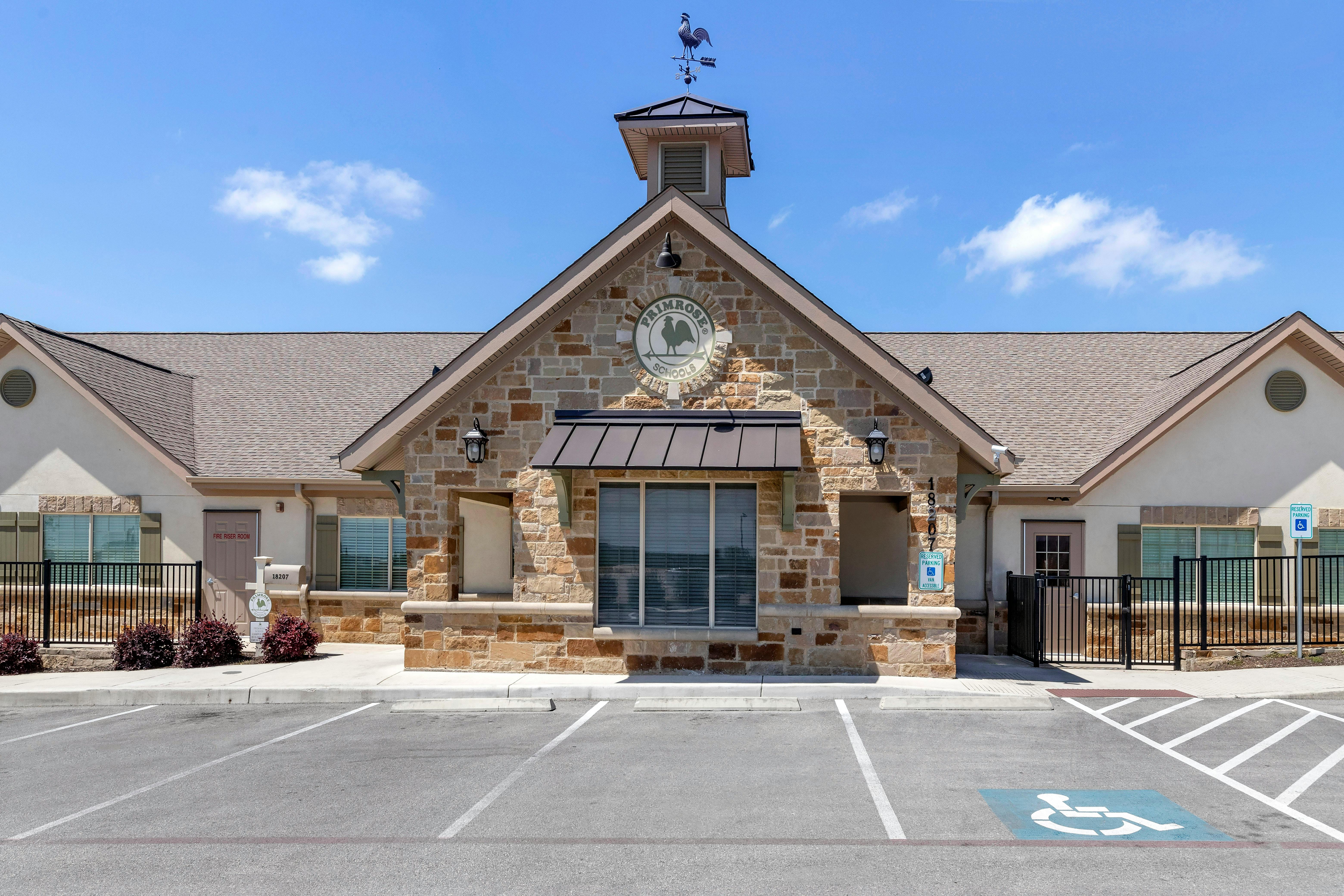 Primrose School building with a stone facade, rooftop weathervane, and parking lot