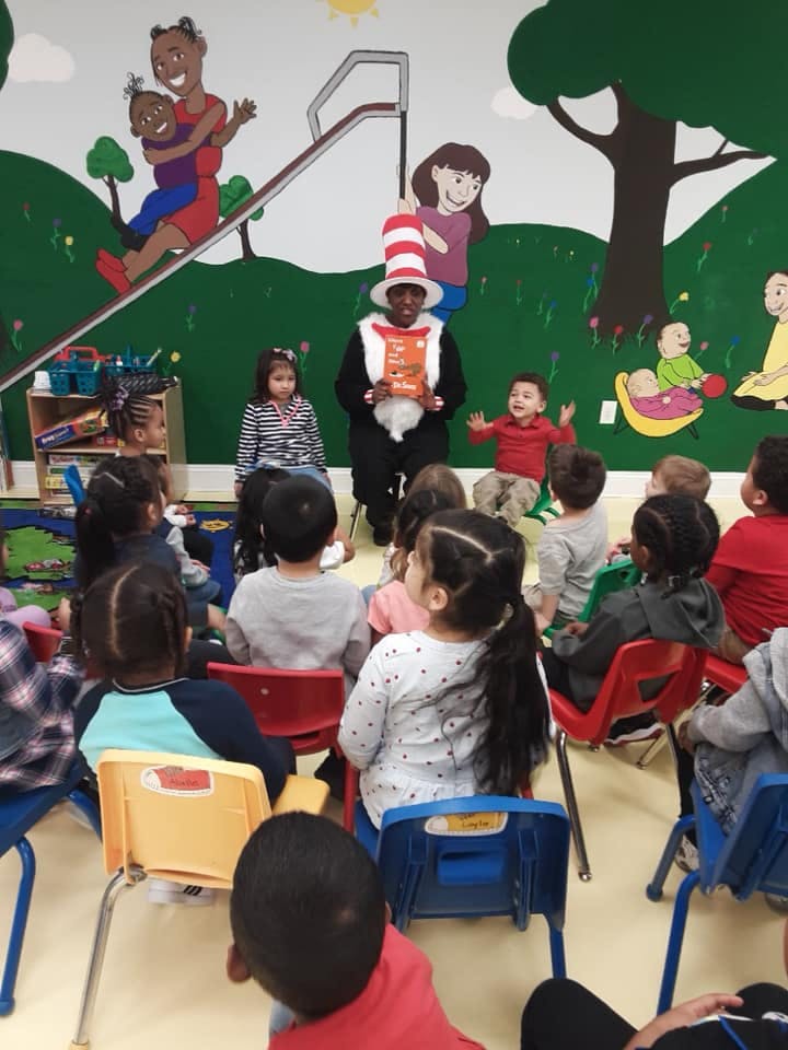 Person in Cat in the Hat costume reading to children in a classroom