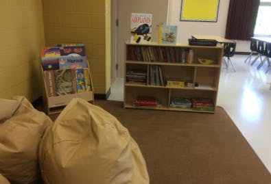 Bean bags on a rug in a classroom with bookshelves