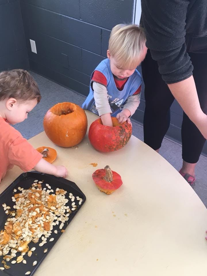 Two children carving pumpkins on a table