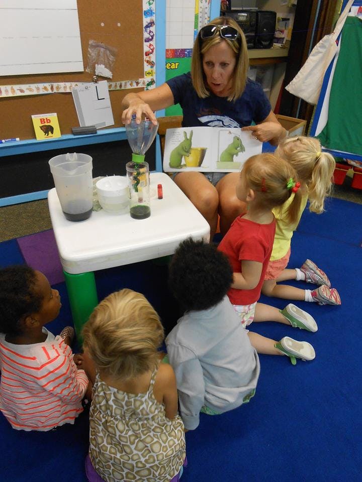 Adult and children gathered around a table with science experiment materials