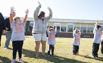 Adult and children with arms raised outdoors