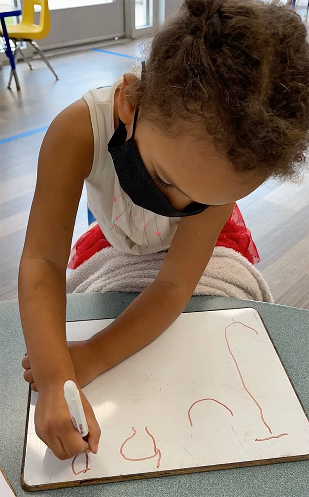 Child drawing on a whiteboard with a marker