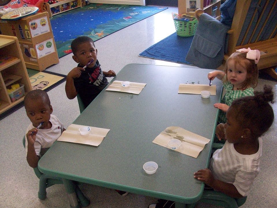 Four children sitting at a table in a classroom