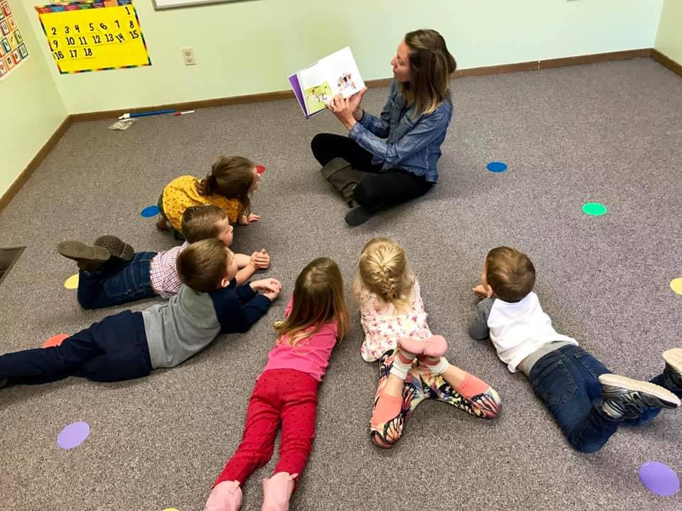 Person reading a book to children in a classroom