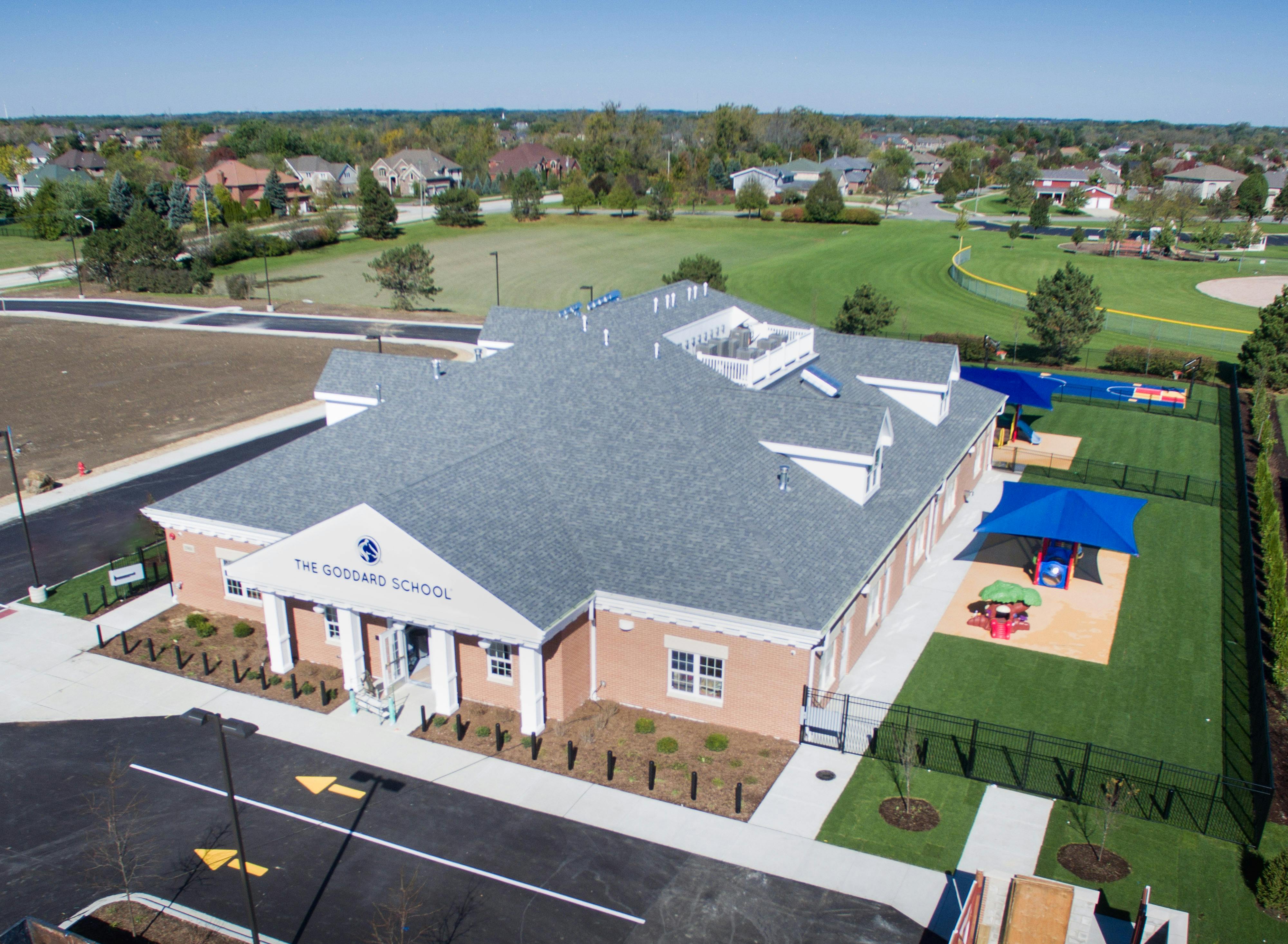 Aerial view of a brick building with a gray roof and a playground