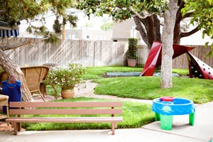 Backyard with a wooden bench, green grass, and play equipment