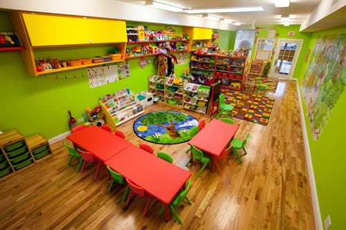 Classroom with red tables, green chairs, and colorful shelves