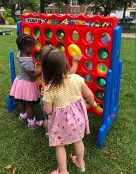 Two children playing with a large Connect Four game