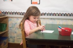 Child sitting at a table looking at a piece of paper
