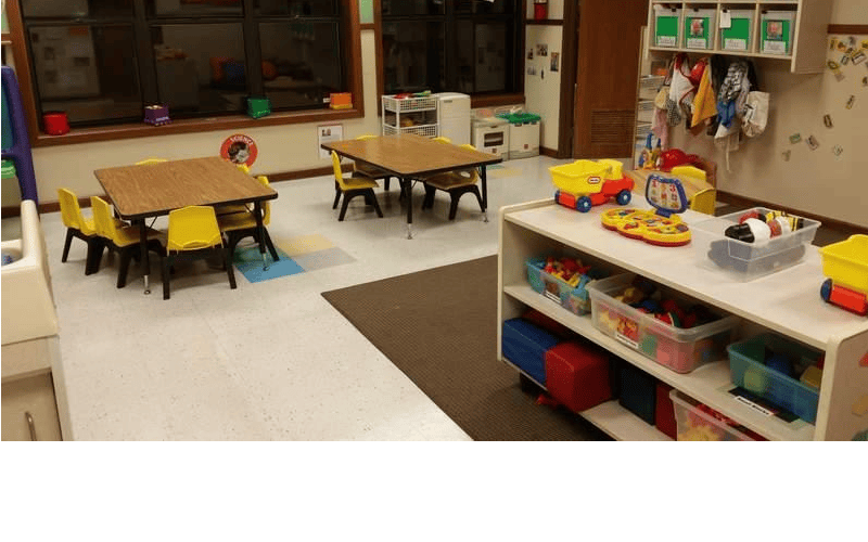 Classroom with child-sized tables, chairs, and shelves full of toys
