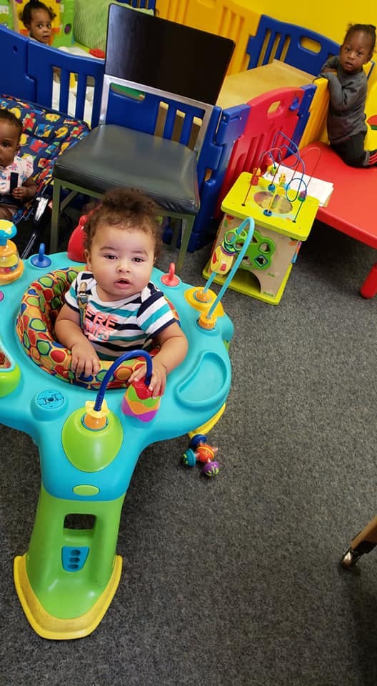 Child in a colorful activity center with other children in the background