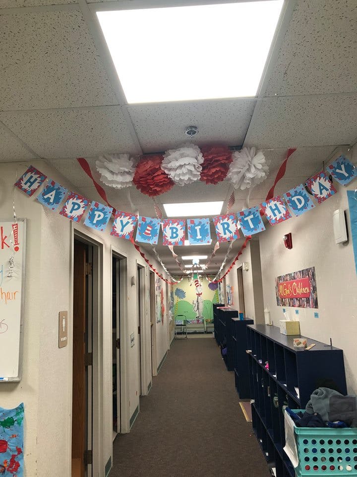 Hallway decorated with a "Happy Birthday" banner and red and white pom-poms