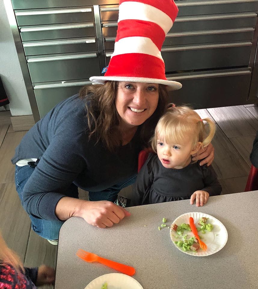 Person in a red and white striped hat with a child at a table