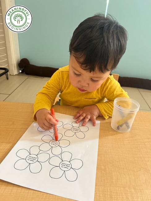 Child coloring in a flower-shaped drawing on a sheet of paper