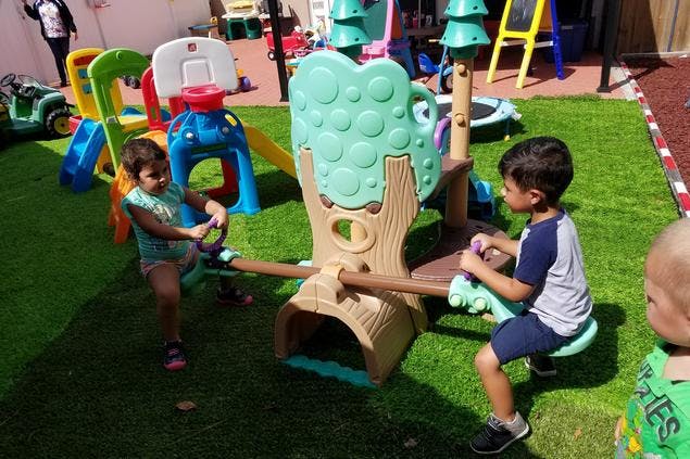 Two children playing on a seesaw in a playground