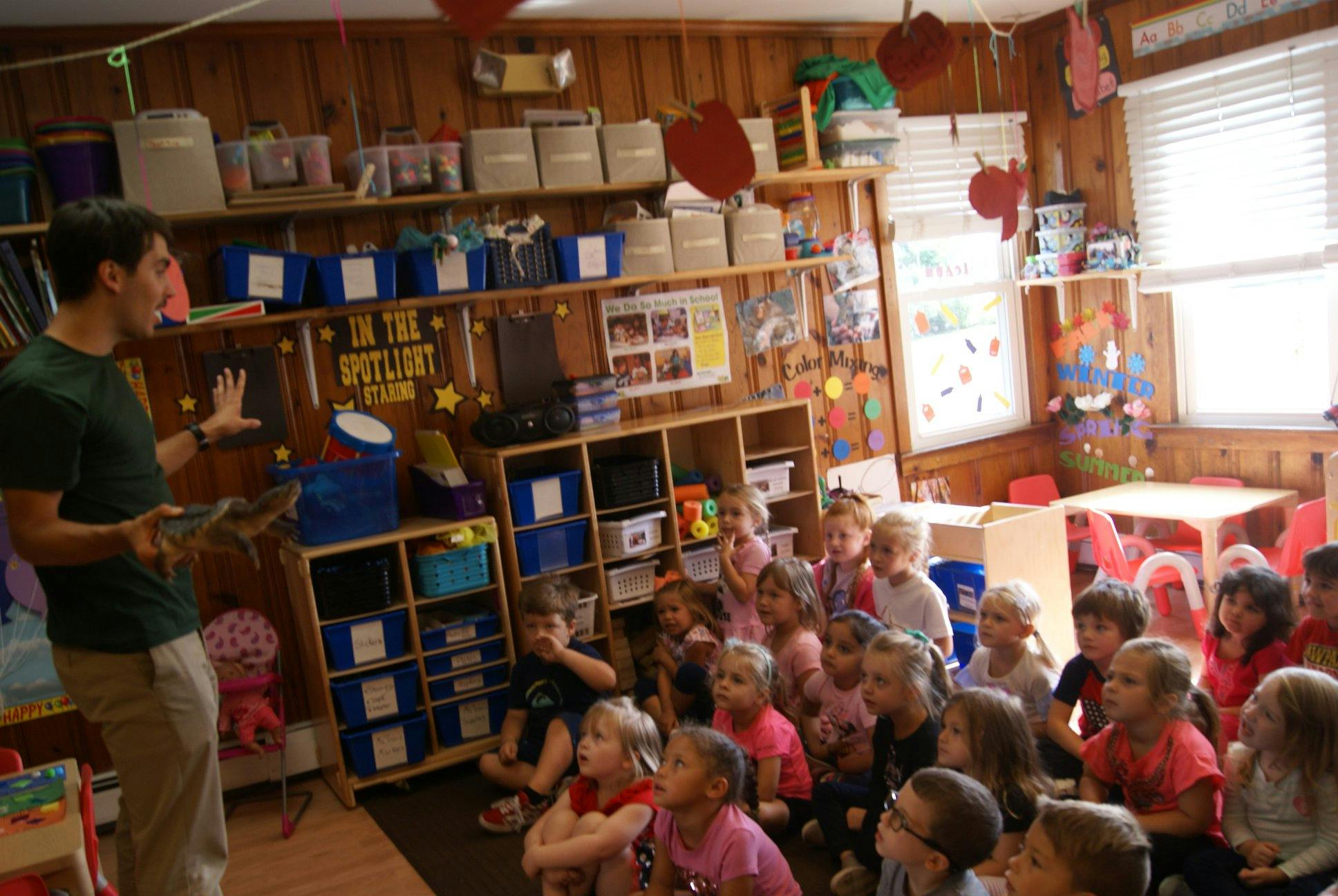 Person speaking to a group of children in a classroom