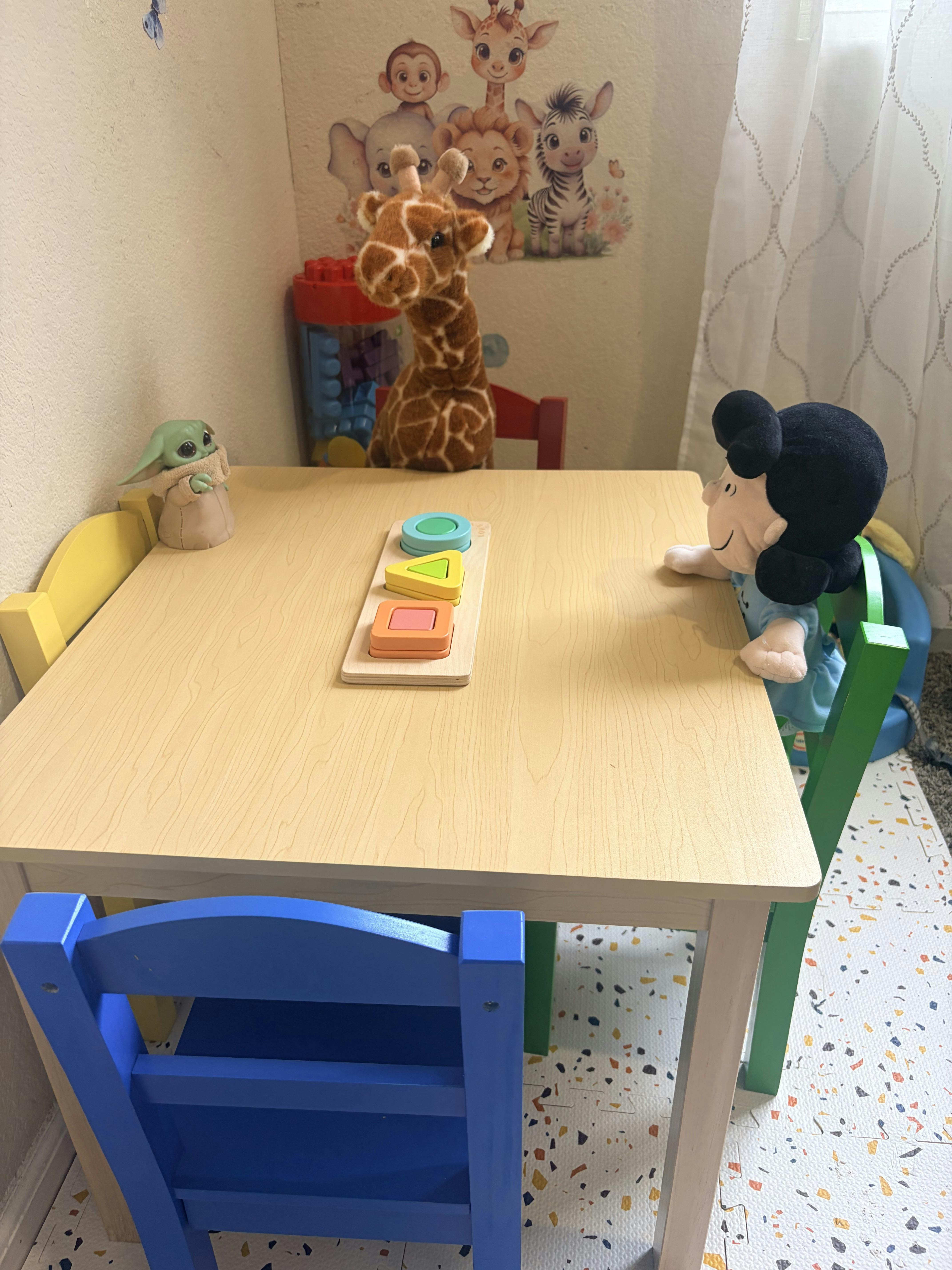 Plush toys sitting at a small child's table with a shape sorting toy
