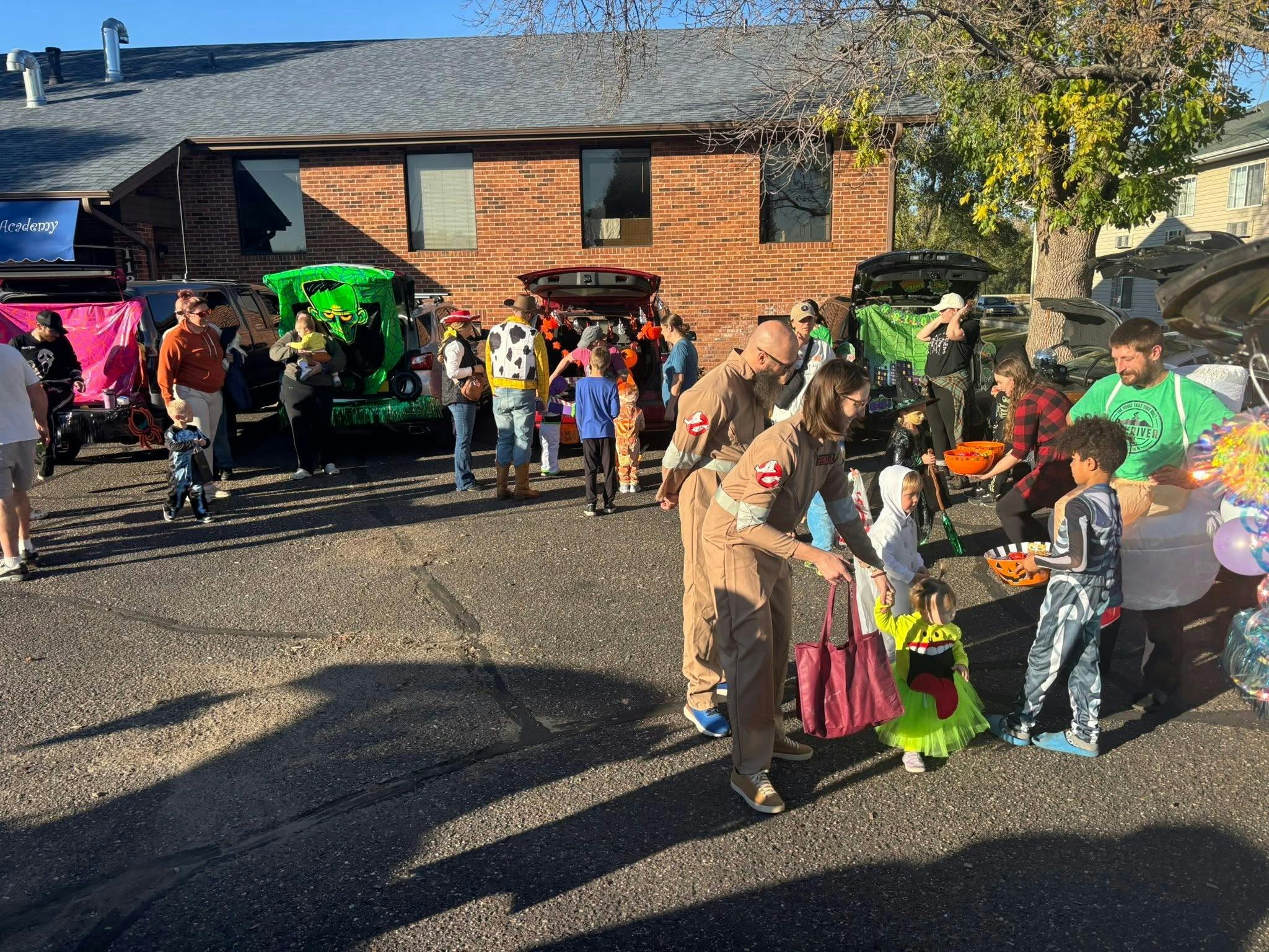 People in costumes participating in a trunk-or-treat event in a parking lot