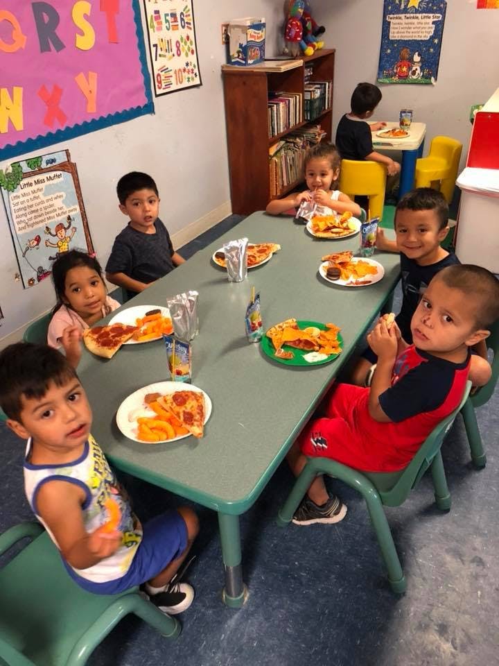 Children eating pizza and snacks at a table