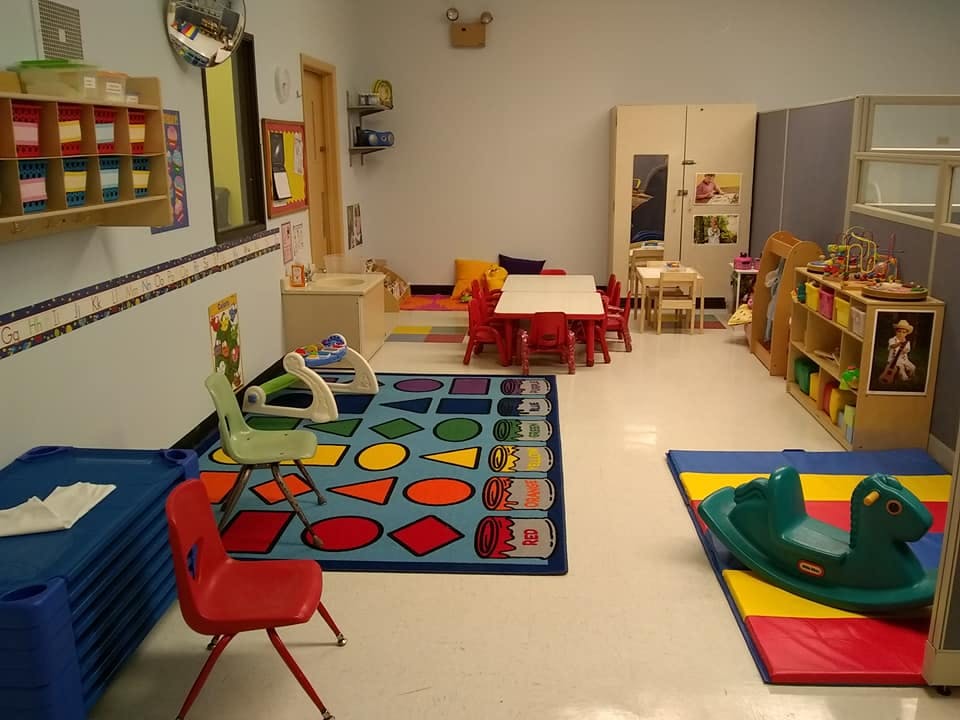 Playroom with small tables and chairs, colorful rugs, and toys